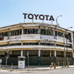 Opuszczony salon Toyoty, symbol miasta duchów na Cyprze, z wybitymi szybami i zniszczoną fasadą.
