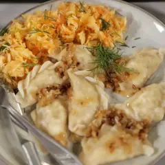 Pyszne pierogi z cebulką i koperkiem, podane z surówką z kiszonej kapusty. Idealne na mandu menu.
