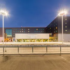 Nowoczesny Courtyard by Marriott, hotel lotniskowy w Warszawie, oświetlony nocą.