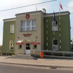 Urząd Miasta Terespol z polską i unijną flagą. Budynek ma zielono-żółtą elewację.