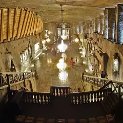 Wielka komora kopalni soli „Wieliczka” z kryształowymi żyrandolami i turystami. Opinie o tym miejscu są zachwycające.