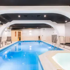 Basen i jacuzzi w hotelu Qubus Wrocław. Obok leżaki, sauna i sprzęt do ćwiczeń.