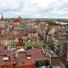 Widok na **Toruń stare miasto** z lotu ptaka. Czerwone dachy kamienic, kościelne wieże i Wisła w tle.
