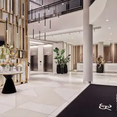 Eleganckie lobby hotelu Radisson Collection Hotel Warsaw z nowoczesnymi windami, recepcją i dekoracjami roślinnymi.