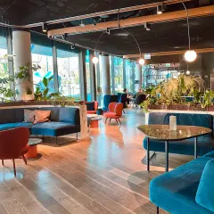 Nowoczesne wnętrze hotelu Puro w Łodzi z wygodnymi, turkusowymi sofami i czerwonymi fotelami.