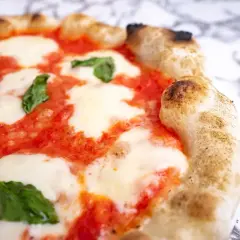 Pyszna pizza parma z rozpływającym się serem mozzarella, sosem pomidorowym i świeżą bazylią. Idealna na włoską ucztę.