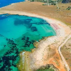 Widok z lotu ptaka na turkusowe morze i piaszczyste bari plaże z rzędami parasoli.
