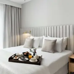 Eleganckie łóżko w pokoju hotelowym, śniadanie na tacy, jak w Royal Tulip Warszawa.