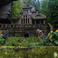 Kamienny domek w skalnym otoczeniu, idealne miejsce na czeska szwajcaria noclegi. Kwitnące kwiaty dodają uroku.