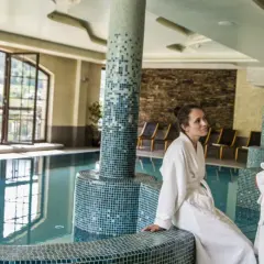 Para relaksu w Hotel Elbrus Spa & Wellness. Para w szlafrokach przy basenie, z widokiem na góry.