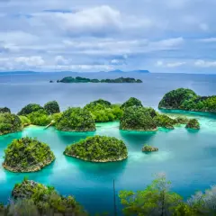 Rajskie krajobrazy Raja Ampat: bujne, zielone wyspy wyrastające z turkusowych wód, tworzące labirynt zatoczek i lagun.
