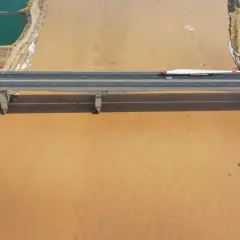 Most gigantycznego łopaty wiatraka transportowany przez most nad mętną wodą rzeki Huang He.