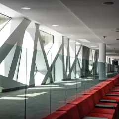 Nowoczesny korytarz z czerwonymi kanapami i geometrycznymi oknami. Hotel Narvil Conference & Spa opinie – idealne miejsce na wydarzenia.