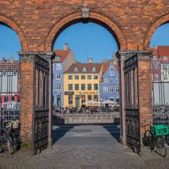 Kolorowe kamienice nad kanałem, ludzie siedzący na murku, rowery przy bramie. Tak wygląda Kopenhaga.