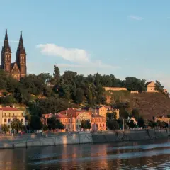 Wyszehrad góruje nad Wełtawą, z dominującą bazyliką i zielonymi wzgórzami.