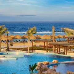 Relaks przy basenie i plaży z parasolami w hotelu Lazuli Marsa Alam. Błękitne morze i palmy tworzą rajski widok.