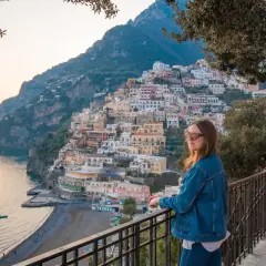 Kobieta podziwia malownicze miasta we Włoszech, Positano, z widokiem na morze i kolorowe domy wznoszące się po zboczu góry.