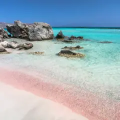 Różowy piasek na Elafonisi Beach, turkusowa woda i skały tworzą rajski krajobraz.