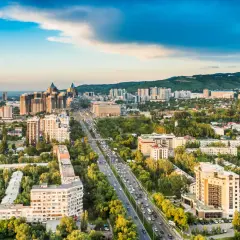 Widok na Almaty, dawną stolicę Kazachstanu, z wieżą telewizyjną w tle i ruchliwą autostradą pośród zieleni.