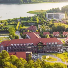 Widok z lotu ptaka na kompleks hotelowy Radisson z czerwonymi dachami, otoczony zielenią i jeziorem.