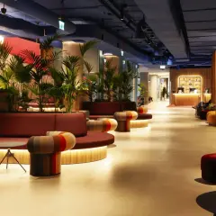 Nowoczesne wnętrze hotelu Mercure Warszawa Centrum z wygodnymi sofami, kolorowymi fotelami i bujną roślinnością.