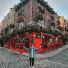 Kobieta pozuje przed słynnym pubem The Temple Bar w Dublinie, stolicy Irlandii. Uliczka wybrukowana kocimi łbami.