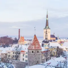 Zimowy widok na średniowieczne wieże i dachy pokryte śniegiem w Tallinnie, stolicy Estonii.