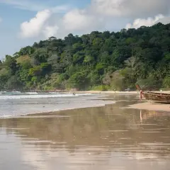 Spokojny dzień na Kata Beach. Długie łodzie odpoczywają na piaszczystym brzegu, a fale delikatnie obmywają brzeg.