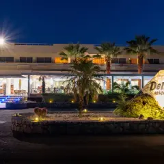 Nocny widok na Delfinia Resort. Podświetlone schody prowadzą do wejścia. Kamienny znak z nazwą hotelu.