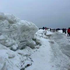 Mikoszewo: imponujące góry lodowe na plaży, ludzie spacerują po zamarzniętym brzegu.