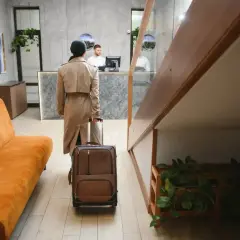 Kobieta z walizką idzie do recepcji. Czy to początek udanego pobytu, jak sugerują pozytywne zenhotels recenzje?