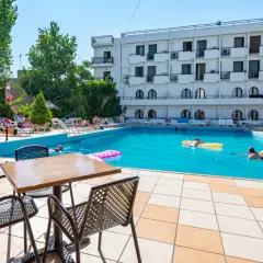 Basen hotelowy, ludzie relaksują się na leżakach i pływają. Wiele pozytywnych heronissos hotel opinie potwierdza ten widok.