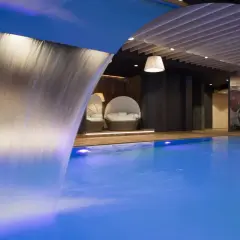 Relaks w basenie z wodospadem w szczawnickich termach. Wygodne leżaki i kolorowa ściana z kwiatami tworzą atmosferę spokoju.