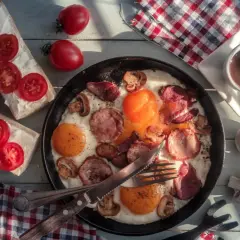 Pyszne polskie śniadanie: jajecznica z kiełbasą i grzybami, kanapki z pomidorami i kawa.