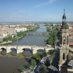 Widok na rzekę Ebro w Saragossie, z kamiennym mostem i wieżą bazyliki w tle.