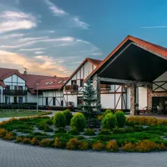 Hotel Mikołajki Leisure & Spa: malowniczy budynek z kamiennymi elementami i drewnianą stolarką, otoczony zadbanym ogrodem.