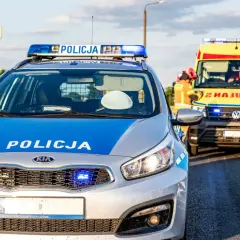 Radiowóz policyjny i karetka na poboczu drogi w Emilianowie. Służby zabezpieczają miejsce zdarzenia.