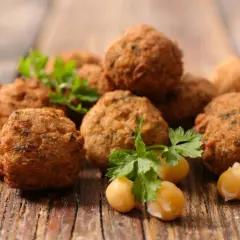 Chrupiące kulki falafel, z ciecierzycą i natką pietruszki, na drewnianym blacie. Falafel co to? To pyszna przekąska!