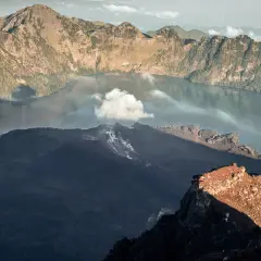 Aktywny wulkan w Indonezji, z dymem unoszącym się z krateru i jeziorem w kalderze.