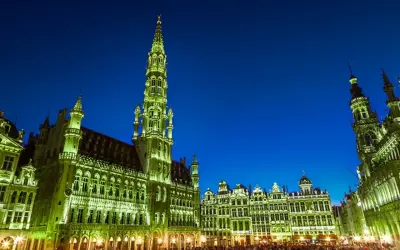 Wieczorem na Grand Place w Brukseli, oświetlone ratusz i kamienice tworzą magiczny widok.