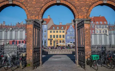 Kolorowe kamienice nad kanałem, ludzie siedzący na murku, rowery przy bramie. Tak wygląda Kopenhaga.