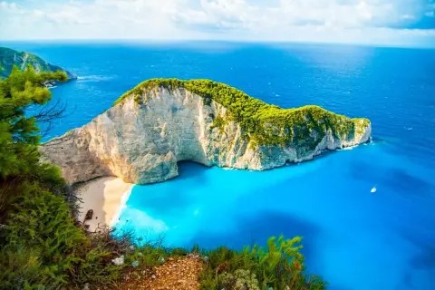 Widok na zatokę Navagio, słynną plażę w Grecji, z klifem porośniętym zielenią i turkusową wodą. Idealne miejsce na wakacje, jak z pocztówki z greckich miast.