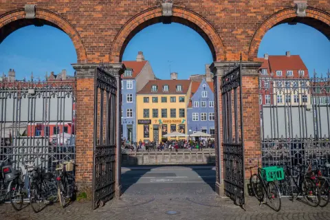 Kolorowe kamienice nad kanałem, ludzie siedzący na murku, rowery przy bramie. Tak wygląda Kopenhaga.