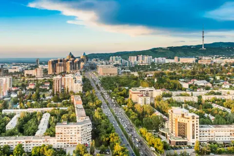 Widok na Almaty, dawną stolicę Kazachstanu, z wieżą telewizyjną w tle i ruchliwą autostradą pośród zieleni.