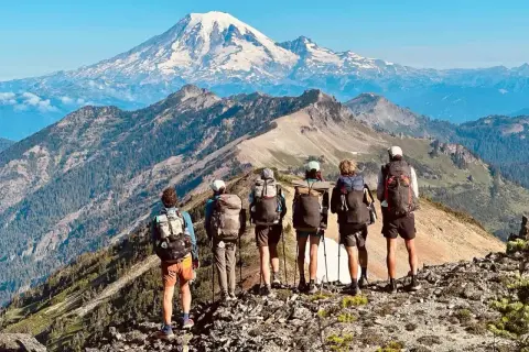Sześcioro turystów z plecakami na grani, podziwiających majestatyczny szczyt. Przygoda na Pacific Crest Trail trwa.