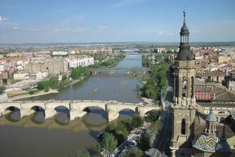 Widok na rzekę Ebro w Saragossie, z kamiennym mostem i wieżą bazyliki w tle.