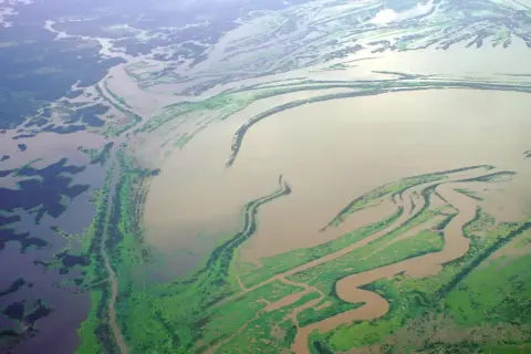 Rozległa delta rzeki, najdłuższa rzeka Azji, z licznymi odnogami i zielonymi wyspami porośniętymi roślinnością.