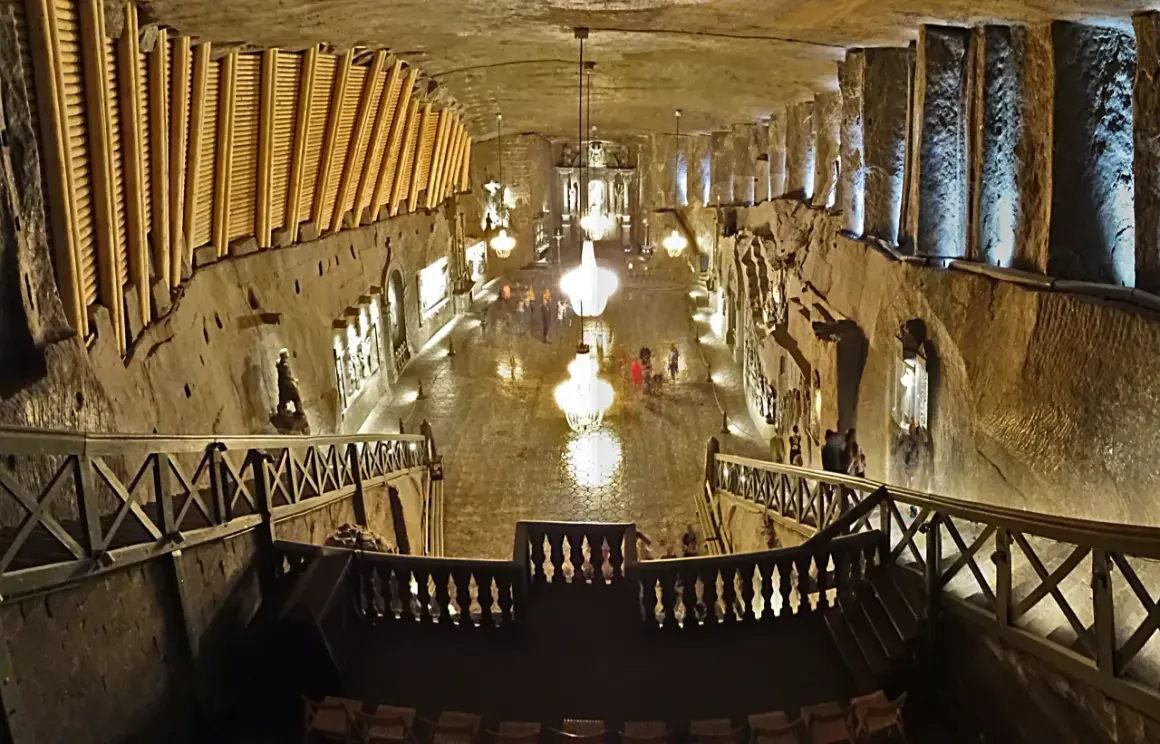 Wielka komora kopalni soli „Wieliczka” z kryształowymi żyrandolami i turystami. Opinie o tym miejscu są zachwycające.