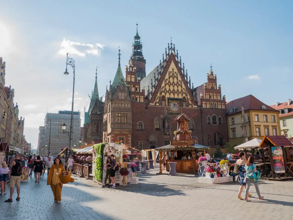 Tętniący życiem plac solny we Wrocławiu. Ludzie spacerują wśród kramów i zabytkowej architektury.