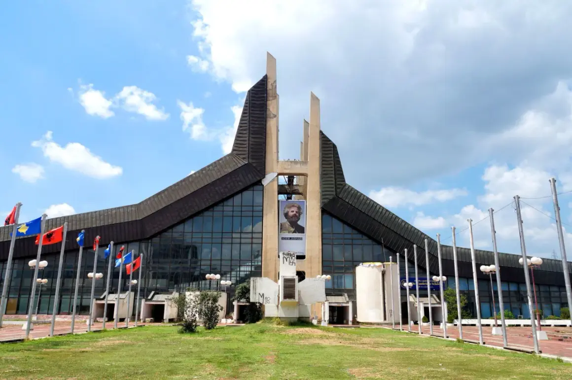 Prisztina, jego stolicą, wita gości monumentalnym budynkiem z portretem Adema Jashari. Flagi powiewają na wietrze.